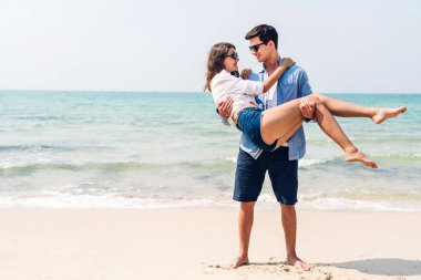 Romantik aşk genç mutlu gülümseme balayı seyahati çift mavi gökyüzü deniz plajında kum üzerinde duruyor birlikte eğleniyorlar ve tropikal plajda dinleniyorlar.