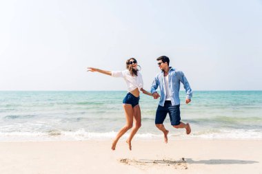 Romantik aşk genç mutlu gülümseme balayı seyahati çift mavi gökyüzü deniz plajında kum üzerinde duruyor birlikte eğleniyorlar ve tropikal plajda dinleniyorlar.