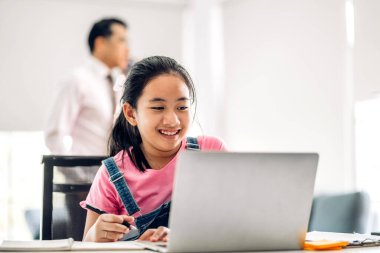 Öğrenci küçük kız öğreniyor ve dizüstü bilgisayara bakıyor ev ödevi yapıyor çevrimiçi eğitim sistemi ile bilgi öğreniyor. Evde öğretmenle çocuk video konferansı