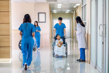Asyalı gülümseyen kadın doktor servisi, küçük kız hastayla konuşma ve danışma konuşmalarına destek oluyor. Oyuncak ayıyı ver ve hastanede bilgi topla.