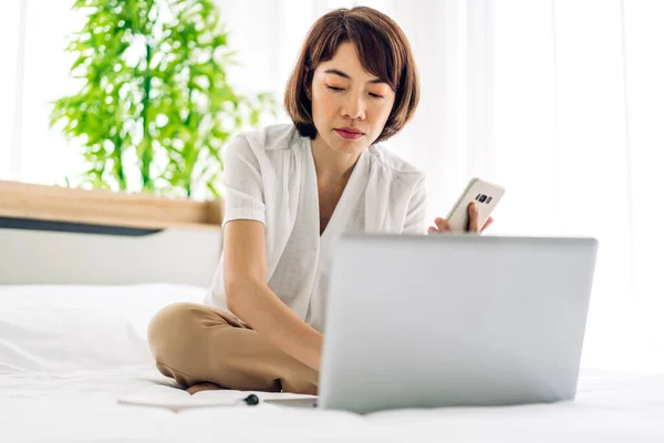 Young smiling happy beautiful asian woman relaxing using laptop computer on sofa at home.Young creative girl working and typing on keyboard.work from home concept