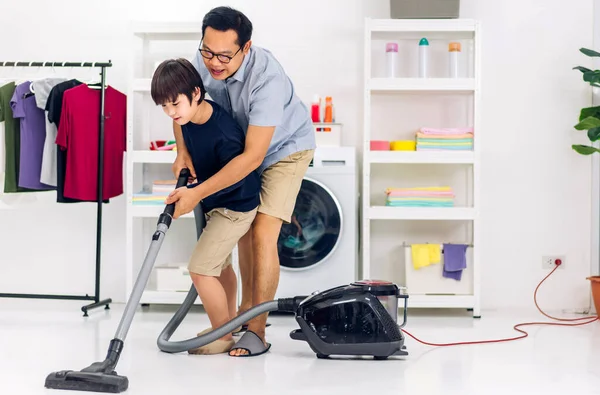 아버지는 아들에게 집안일을 즐겁게 가르친다 청소와 청소를 집에서 청소하는 진공청소기로 — 스톡 사진