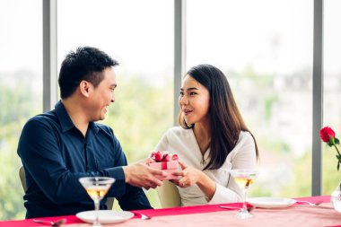 Sevgililer Günü 'nü birlikte kutlarken eğlenen ve gülümseyen romantik çift. Sevgililer Günü' nde kız arkadaşına hediye paketi veren yakışıklı adam.