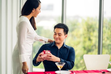 Sevgililer Günü 'nü birlikte kutlarken eğlenen ve gülümseyen romantik çift. Sevgililer Günü' nde kız arkadaşına hediye paketi veren yakışıklı adam.