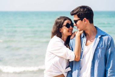 Romantik aşk genç mutlu gülümseme balayı seyahati çift mavi gökyüzü deniz plajında kum üzerinde duruyor birlikte eğleniyorlar ve tropikal plajda dinleniyorlar.