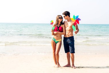 Romantik aşk genç mutlu gülümseme balayı seyahati çift mavi gökyüzü deniz plajında kum üzerinde duruyor birlikte eğleniyorlar ve tropikal plajda dinleniyorlar.