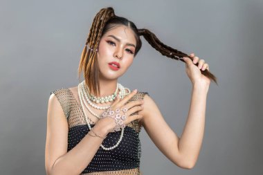 Gülümseyen, neşeli, güzel, Asyalı moda kadını. Siyah moda kıyafetleriyle gülümsüyor. Seksi kız düşüşü. Gri arka planda Kore modasına uygun makyaj tasarımı.