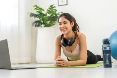 Portre sporu spor, spor kıyafetleri içinde ince kadın, rahatlama ve yoga yapan kız, yatak odasında dizüstü bilgisayarla spor yapıyor. Diyet konsepti. Fitness ve sağlıklı.