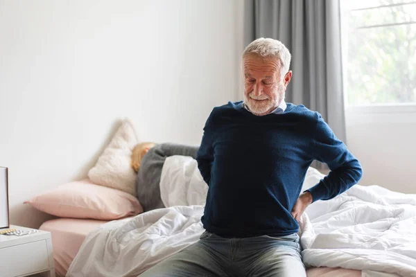 stock image Sick unhappy senior adult elderly man touching her muscle injury Lower back suffering from muscles back pain at home.physical injury and healthcare problem