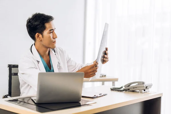 病院でノートパソコンを操作する聴診器と一様の制服を着たアジア人医師 — ストック写真