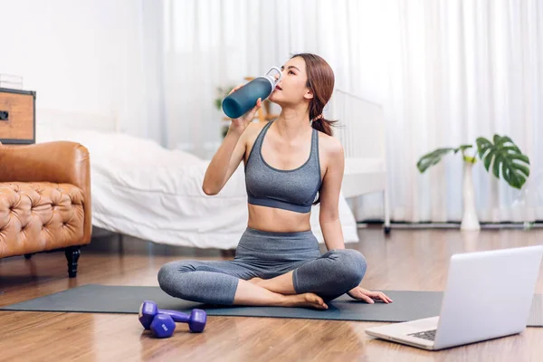 Portrait sport beauty body slim woman drinking water from a bottle while relax and feeling fresh at home.Healthy lifestyle concept