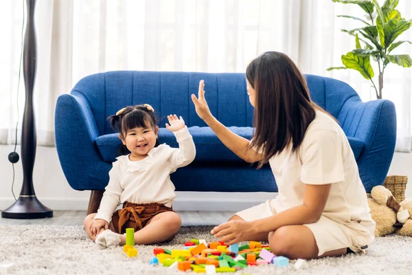 Portrait of enjoy happy love asian family mother with little asian girl smiling activity learn and skill brain training play with toy build wooden blocks board education game at home