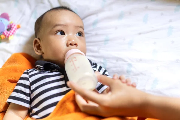 白い寝室でかわいい息子にミルクの母供給ボトル 家族の概念の愛 — ストック写真