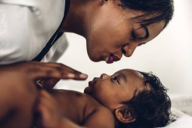 Mutlu bir aşk portresi Afro-Amerikan anne, sevimli bir Afrikalı Amerikalı bebekle oynuyor. Anne, tatlı oğluyla beyaz bir odada iyi vakit geçiriyor. Siyah aile sevgisi.