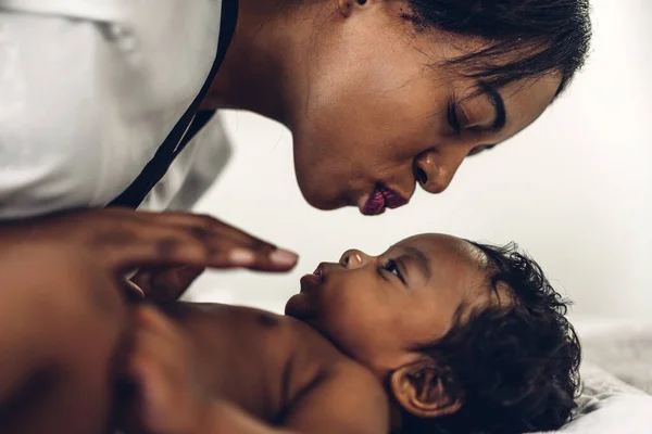 幸せな愛の家族の肖像画アフリカ系アメリカ人の母親は愛らしい小さなアフリカ系アメリカ人の赤ちゃんと遊んでいます お母さんは白い寝室で楽しい時間をかわいい息子の瞬間とキス 黒人家族の愛 — ストック写真