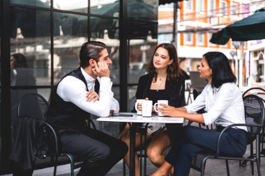Bir grup neşeli genç arkadaş buluşmayı tartışıyor ve birlikte kahve içerek eğleniyorlar. Kafe masasında ve restoranda karışık ırkçı insanlar oturuyor.