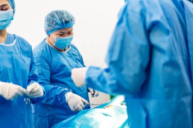 Profesyonel anestezi uzmanı doktor tıp ekibi ve asistanı modern hastane acil servisinde cerrahi ekipmanla jinekolojik ameliyata hazırlanıyor.