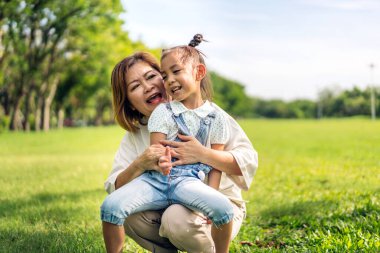 Mutlu aşk portresi Asyalı büyükanne ve Asyalı küçük tatlı kız yaz parkında rahatlayın. Gülen büyükanneleri ve büyükbabalarıyla birlikte gülümseyen genç kız. Aile ve beraberlik.