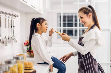 Mutlu aşk portresi. Asyalı anne ve küçük Asyalı kız çocuk gülümsüyor ve evde mutfakta birlikte kahvaltı hazırlıyorlar.