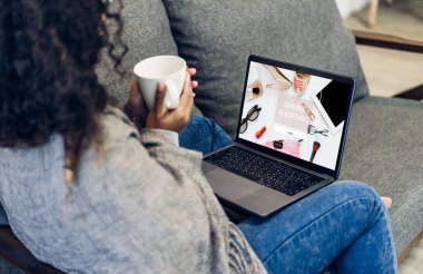 Afrikalı kadın portresi rahatlamak için dizüstü bilgisayar teknolojisini internet üzerinden moda alışverişi için kullanın. Afrikalı genç bir kız alışveriş saati satışından ve evden bir şeyler satın almaktan zevk alır. İnternet üzerinden alışveriş kavramı.