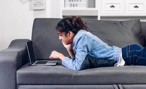 stock image Young smiling happy beautiful asian woman work relaxing using laptop computer on sofa at home.Young creative girl working and typing on keyboard.work from home concept