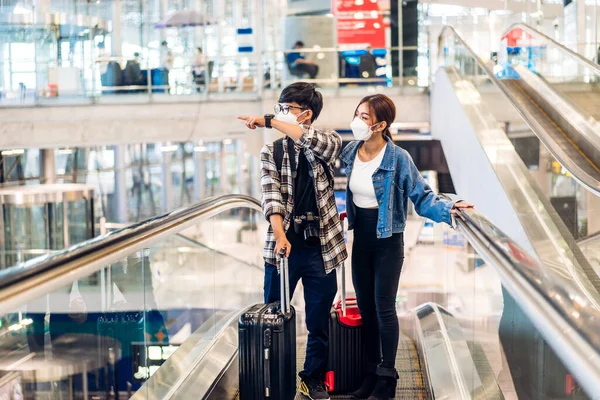 手術用マスク顔保護を身に着けているコロナウイルスの検疫で若い幸せなカップル旅行者は 国際線ターミナル空港で長い旅行休暇のフライトの前にパスポートとチケットを保持します — ストック写真