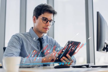 İş dünyasının finansal yatırım verilerinin ekran gelişimine bakan teknoloji dijital tablet bilgisayarı kullanarak rahatlayan hippi iş adamı, ofisteki iş büyümesi grafiğini ve grafiğini çıkarıyor.