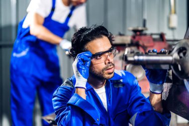 Profesyonel iş gücü mühendisi teknisyeni mavi güvenlik üniforması giyen işçi işçi fabrika üretim hattında ağır makinelerle çalışıyor. İş sektörü.