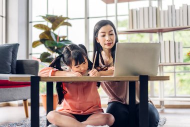 Anne ve Asyalı küçük kız öğreniyor ve online eğitim ile bilgisayar incelemesi yapıyor. Öğrenci evde eğitim bilgisini arıyor. Eğitim