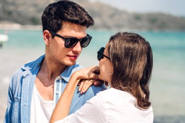 Romantik aşk genç mutlu gülümseme balayı seyahati çift mavi gökyüzü deniz plajında kum üzerinde duruyor birlikte eğleniyorlar ve tropikal plajda dinleniyorlar.