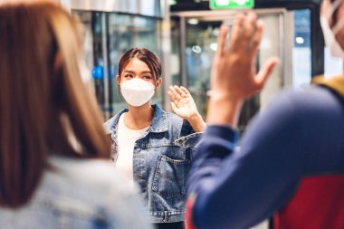 Coronavirus için karantinaya alınan genç bir çift, ameliyat maskesi takarak korunuyor. Uluslararası havaalanındaki uzun yolculuk sonrası arkadaşlarıyla selamlaşıyorlar.
