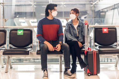 Coronavirus yüzünden karantinada olan genç mutlu bir çift cerrahi maske takıyor. Pasaport ve bilet, Uluslararası Terminal Havaalanı 'nda uzun süreli tatil uçuşundan önce.
