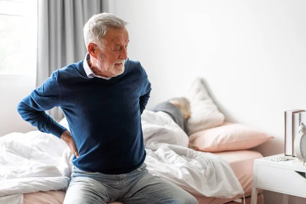 Sick unhappy senior adult elderly man touching her muscle injury Lower back suffering from muscles back pain at home.physical injury and healthcare problem