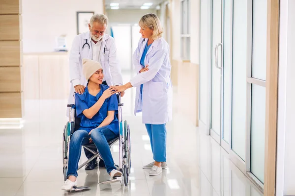Professional medical doctor team with stethoscope in uniform discussing with patient woman with cancer cover head with headscarf of chemotherapy cancer in hospital.health care concept