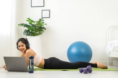 Portre sporu spor, spor kıyafetleri içinde ince kadın, rahatlama ve yoga yapan kız, yatak odasında dizüstü bilgisayarla spor yapıyor. Diyet konsepti. Fitness ve sağlıklı.