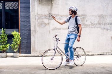 İş seyahati bisikleti konsepti işe giderken bisiklet sürerken sırt çantasıyla gezen sıradan hippi yakışıklı iş adamının portresi.