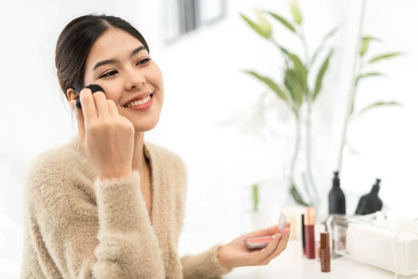 Smiling of young beautiful pretty asian woman clean fresh healthy white skin.asian girl holding make-up brushes and make up on face with cosmetics set at home.facial beauty