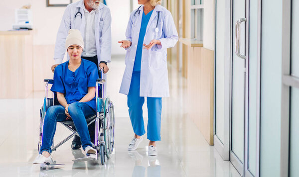 Профессиональная команда врачей со стетоскопом в форме обсуждения с пациенткой с раком покрывает голову платком рака химиотерапии в больнице.