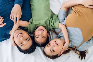 Mutlu bir aşk portresi. Asyalı bir aile babası ve annesi kucaklıyor. Küçük tatlı Asyalı bir kız çocuğu gülümsüyor ve evde eğleniyor.