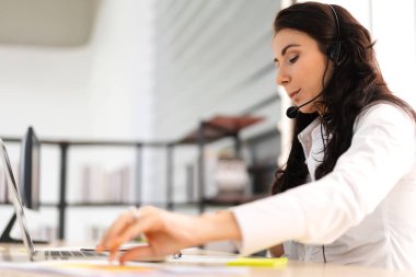 Happy womn çağrı merkezi gülümseyen işletme operatörü müşteri çağrı merkezindeki masaüstü bilgisayarında çalışan ve kulaklıkla konuşan telefon hizmetleri acentesine yardım