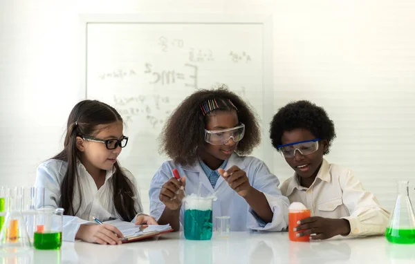 Group of teenage student learn with teacher and study doing a chemical experiment and holding test tube in hand in the experiment laboratory class on table at school.Education concept