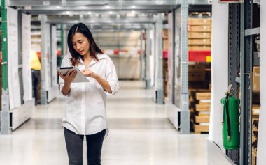 Tablet üzerindeki portre mühendisi kadın nakliyat emri ayrıntıları raflarda malzeme ve malzeme kontrolü fabrika deposunda malzeme envanteriyle birlikte. Lojistik endüstrisi ve iş ihracatı