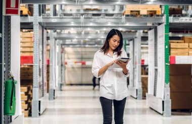 Tablet üzerindeki portre mühendisi kadın nakliyat emri ayrıntıları raflarda malzeme ve malzeme kontrolü fabrika deposunda malzeme envanteriyle birlikte. Lojistik endüstrisi ve iş ihracatı