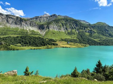 Cormet de Roselend, turkuaz suyla göl, bulutlar ve mavi gökyüzü.