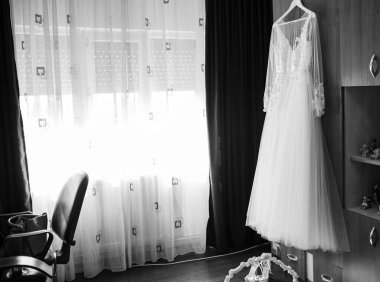 Siyah beyaz gelinlik bir şifonyerin kapısında asılı.