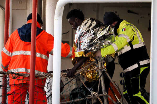 Мигрант покидает корабль в сопровождении добровольцев гражданской защиты. Немецкое спасательное судно "Морской глаз-4" прибывает в порт Неаполя со 109 мигрантами на борту, в том числе 35 несовершеннолетних, 18 женщин, одна из которых беременна, а две мертвы.