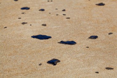 Kumsalda kumdaki petrol lekeleri.