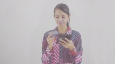 Güvenli bankacılık için kredi kartı kullanan mutlu genç bir kız, çevrimiçi alışverişler, cep telefonu ödemeleri, beyaz arka planda duran akıllı telefonlardan yapılan işlemler. E-bankacılık uygulama hizmeti çevrimiçi güvensiz ödeme,