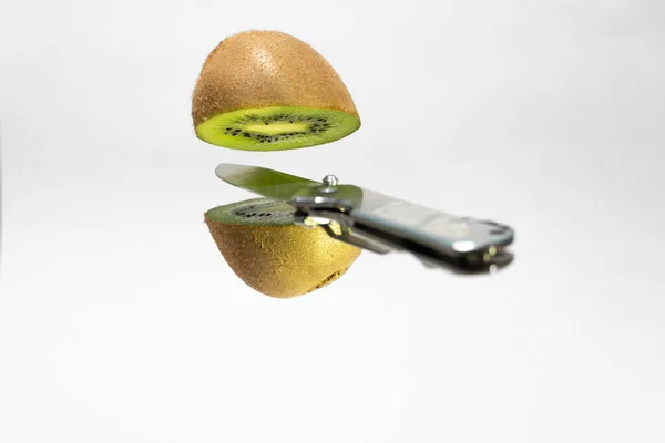 Silver knife cutting floating kiwi. Creative fruit concept