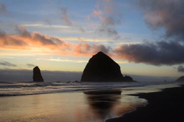 A deserted Cannon Beach, Oregon with Haystack Rock under a beautiful sunset.